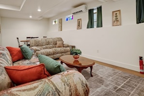 Ein Wohnzimmer mit gemusterten Sofas, einem Couchtisch und einem Essbereich mit Stühlen und Tisch.