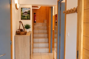 A wooden staircase leading to a second floor with a fire extinguisher on the wall and a framed picture above. - New Listing (Chamonix-Mont-Blanc)