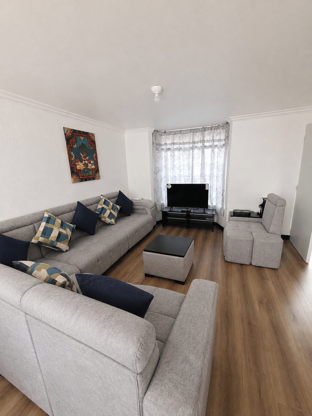 Una sala moderna con un sofá seccional gris, una mesa de centro y un sillón gris.