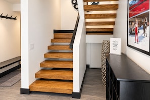 A modern staircase with wooden steps and black handrails, leading to a landing with a framed welcome sign. - Queen Esther Townhome by KBM (Park City)