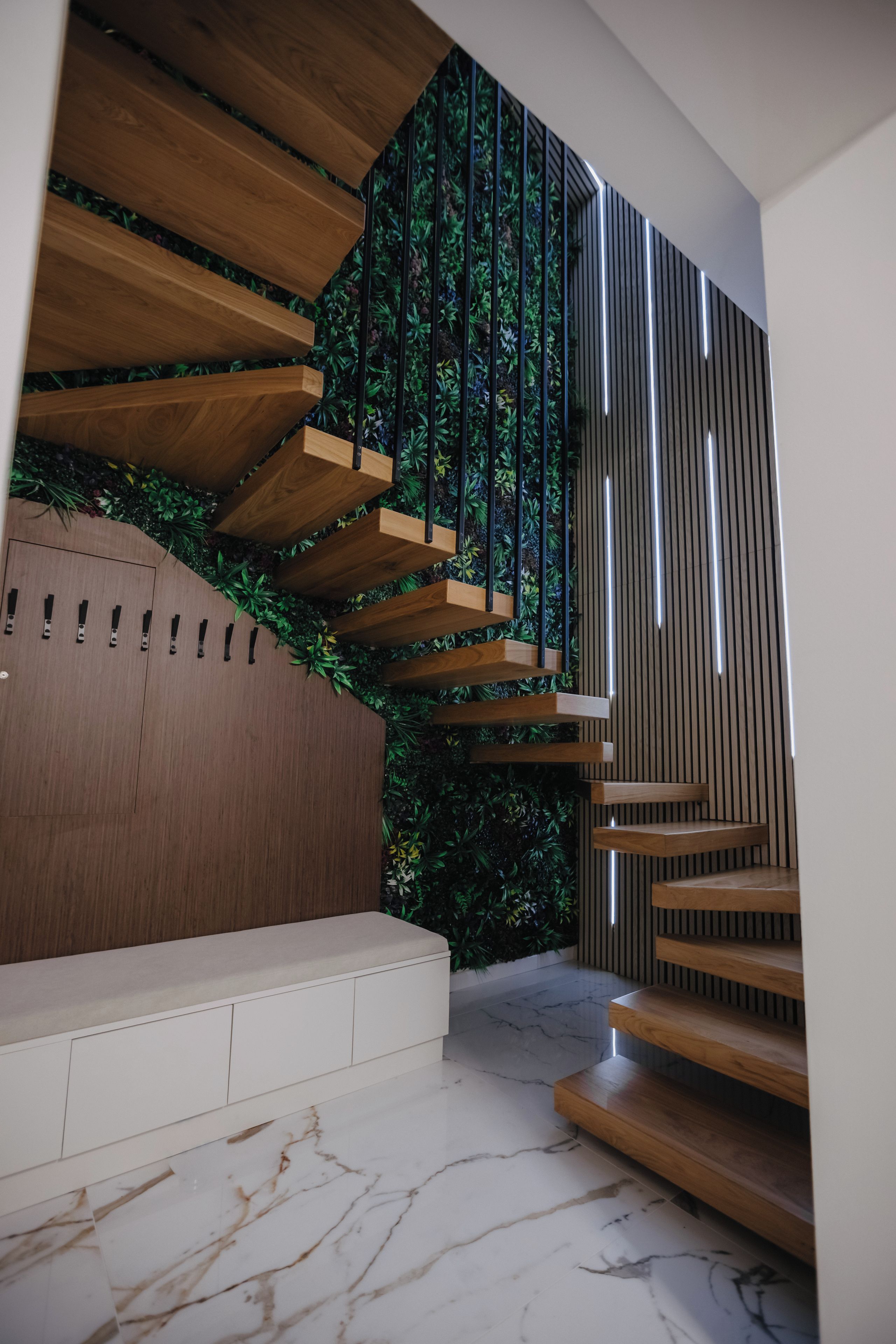 A modern staircase with wooden steps and a green vertical garden.