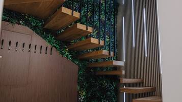 A modern staircase with wooden steps and a green vertical garden.