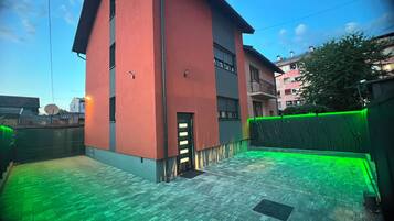 Un edificio con fachada roja, techo plano y patio empedrado.