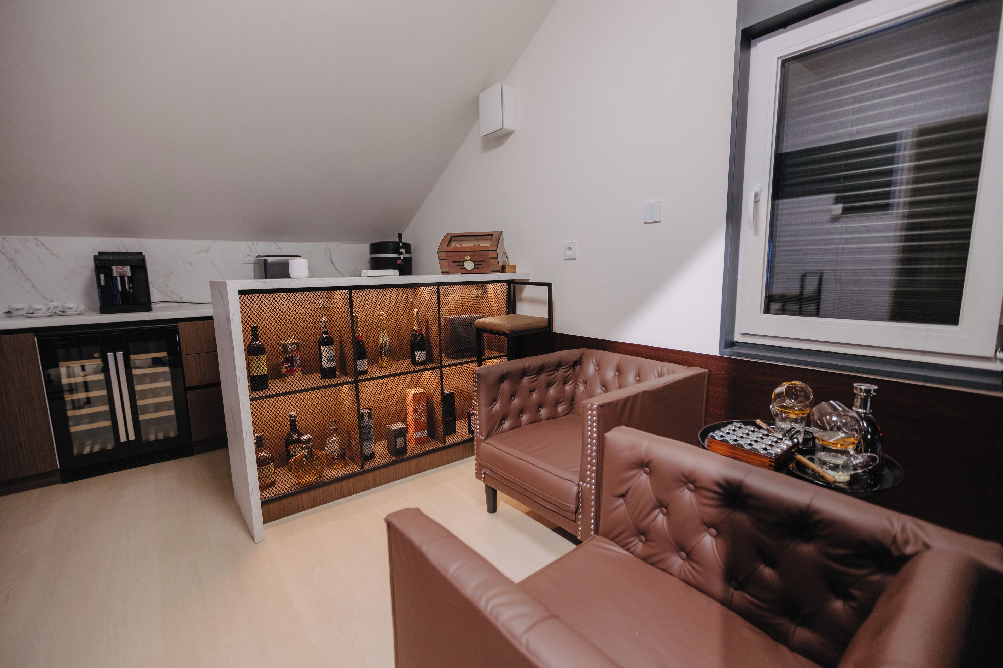 A modern living space with a brown leather sofa, a coffee machine, and a wine rack.