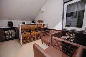 A modern living space with a brown leather sofa, a coffee machine, and a wine rack.