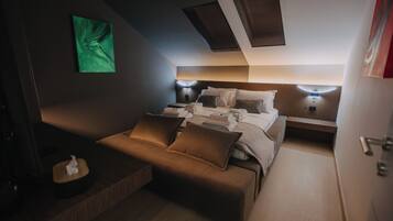 Una habitación de hotel compacta con cama, mesitas de noche, un pequeño sofá y un cuadro abstracto verde en la pared.