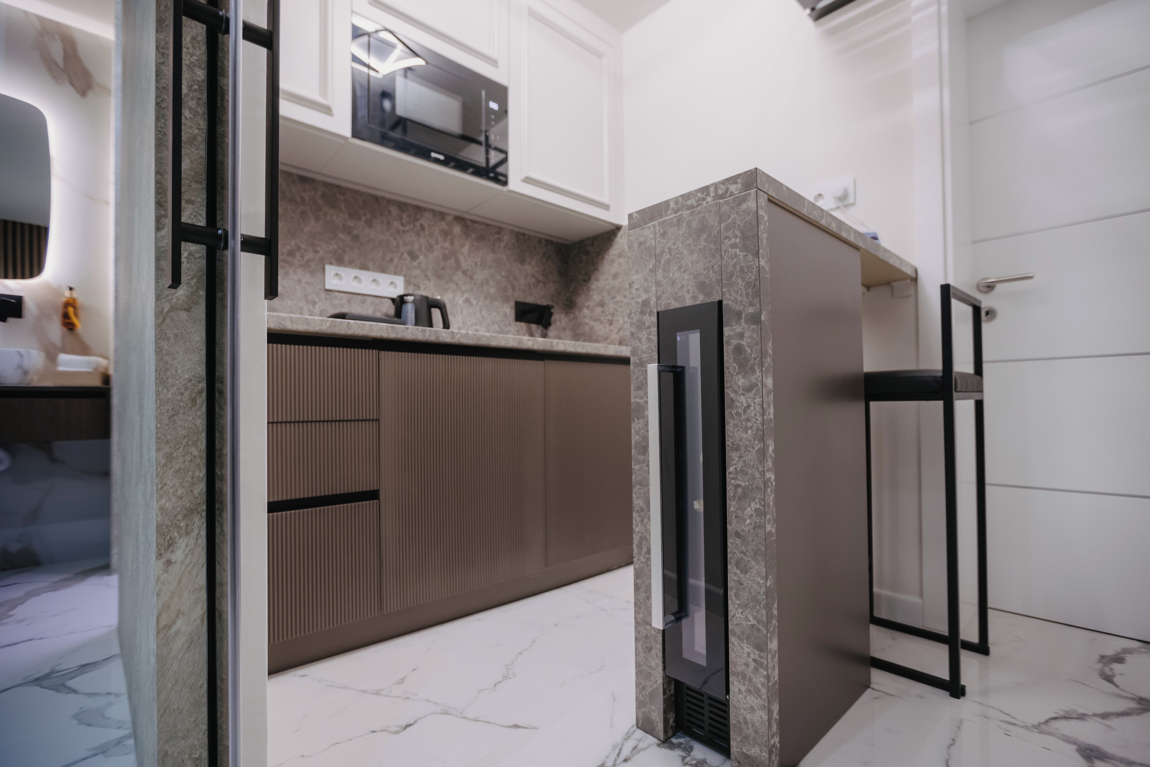 A modern kitchen with a marble countertop, built-in oven, and a sleek black refrigerator.