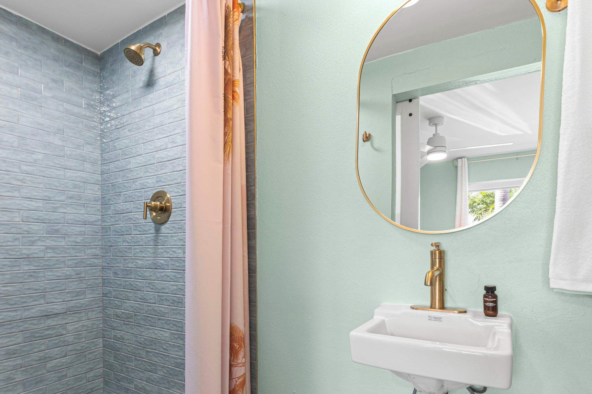 A bathroom with a shower, a sink, and a mirror.