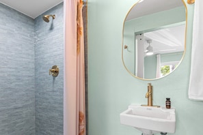 Ein Badezimmer mit Dusche, Waschbecken und Spiegel.