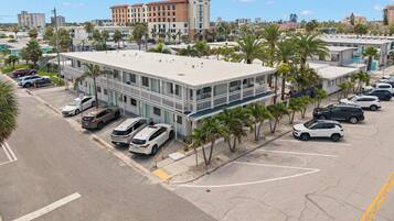 Un hôtel doté d’un parking, de plusieurs voitures et de palmiers.