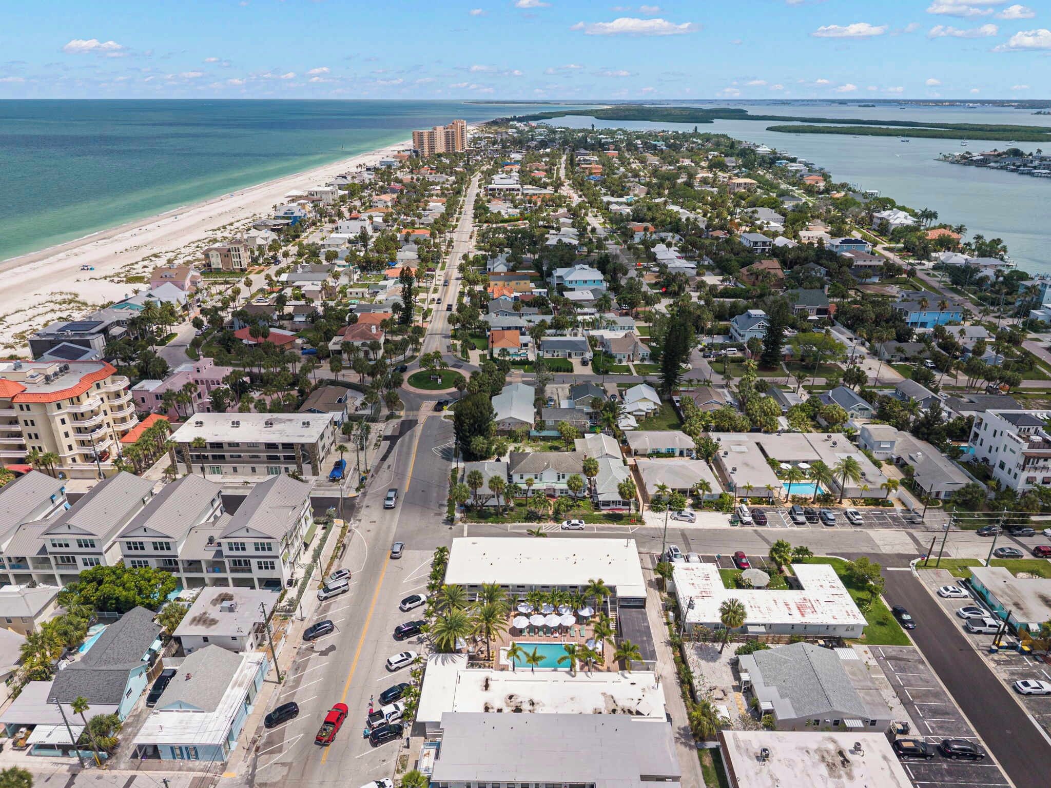 A coastal town with a beach, residential buildings, and a road leading to the sea.