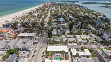 A coastal town with a beach, residential buildings, and a road leading to the sea.