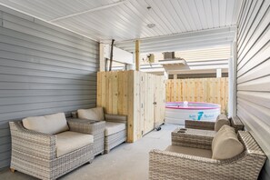Une terrasse extérieure avec des meubles en osier, un jacuzzi et une clôture en bois.