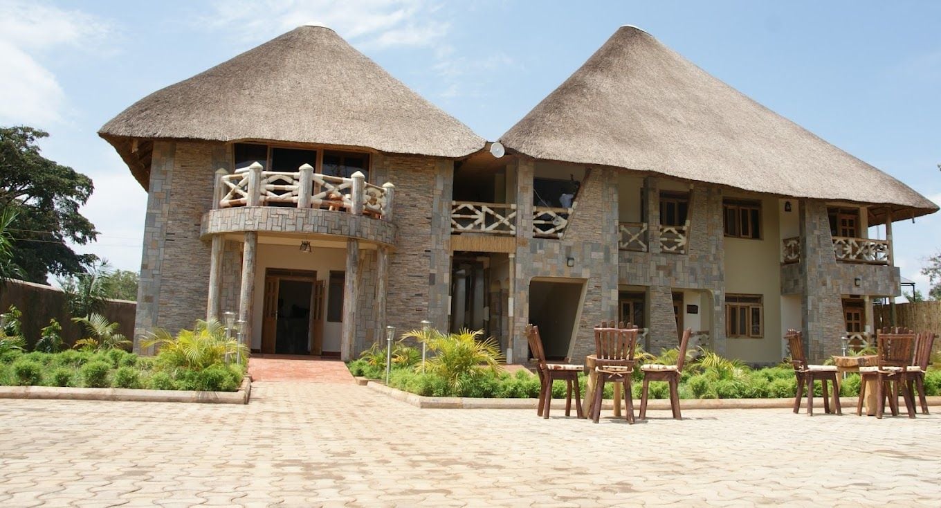 A two-story building with thatched roofs and stone walls, featuring a balcony with wooden railings.
