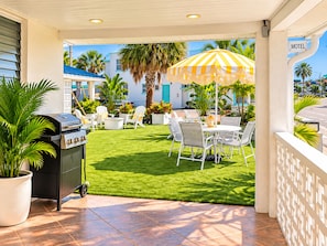 A patio with a grill, outdoor seating, and a 'Motel' sign. - Sunny Beach Inn - Ebb Tide Inn (Treasure Island)