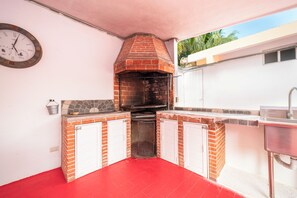 A brick-built outdoor kitchen with a clock, a sink, and a red floor. - Private Villa Pool and Tennis Court 7BR (Cancún)