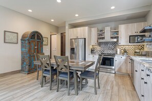 A modern kitchen with a dining area, featuring a large island, stainless steel appliances, and light wood cabinetry. - Luxury 2BR Condo at Quivira Los Cabos (Cabo San Lucas)