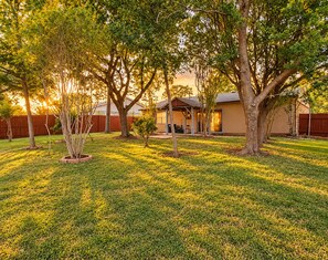 A residential backyard with a house, a covered patio, and a wooden fence. - Your Extended Stay Spot (Arlington)