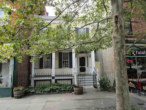 A two-story building with a white facade, a front porch, and a visible storefront with a sign.