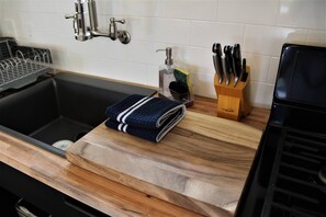 A kitchen with a wooden countertop, a sink, and a knife block. - Private Jacuzzi Surrounded by Oaks Trees (Three Rivers)