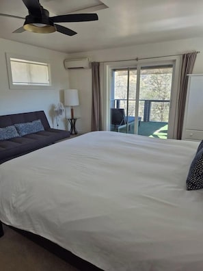 A hotel room with a large bed, a ceiling fan, a window, and a view of the outdoors. - Private Jacuzzi Surrounded by Oaks Trees (Three Rivers)