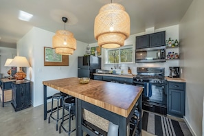 A modern kitchen with a central island, black cabinetry, and a large stove. - Private Jacuzzi Surrounded by Oaks Trees (Three Rivers)