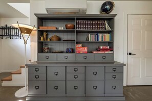 A grey storage unit with multiple drawers and shelves, containing books, a globe, and decorative items. - Private Jacuzzi Surrounded by Oaks Trees (Three Rivers)