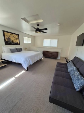 A bedroom with a bed, a dresser, a sofa, a ceiling fan, and a window. - Private Jacuzzi Surrounded by Oaks Trees (Three Rivers)
