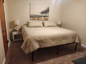 Ein Schlafzimmer mit einem Bett, Nachttischen, Lampen und einem Bild an der Wand.