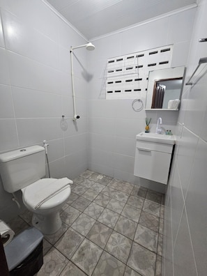 A bathroom with a toilet, shower, sink, and mirror. - New Listing (João Pessoa)