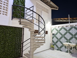 A spiral staircase leading to a second floor, a tiled wall with a geometric pattern, and a small sink with a plant beside it. - New Listing (João Pessoa)