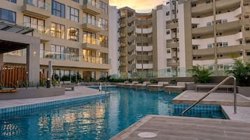 A modern hotel with a swimming pool, multiple balconies, and a courtyard.