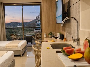 A hotel room with a balcony, a dining area with a sink, and a view of a construction site. - Apartment with luxury Ocean View (Gaira)