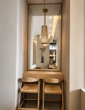 A modern dining area with a wooden table and chairs, a hanging pendant light, and a mirror reflecting the room. - Apartment with luxury Ocean View (Gaira)