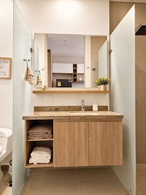 Ein modernes Badezimmer mit einem Holzkosmetikschrank, einem Waschbecken und einem Spiegel.