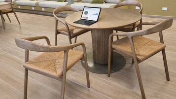 A meeting room with a round table, four chairs, and a laptop displaying a chart.