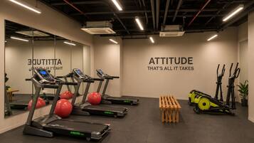 Une salle de sport équipée de tapis de course, de ballons d’exercice et d’un mur orné de messages motivants.