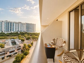 A balcony with a view of high-rise buildings, a small table with cards, and two wicker chairs. - Apartment with luxury Ocean View (Gaira)