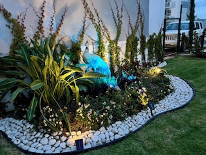 A landscaped garden with a variety of plants, a bird sculpture, and a pathway of white stones. - New Listing (Galaxia la Calera)