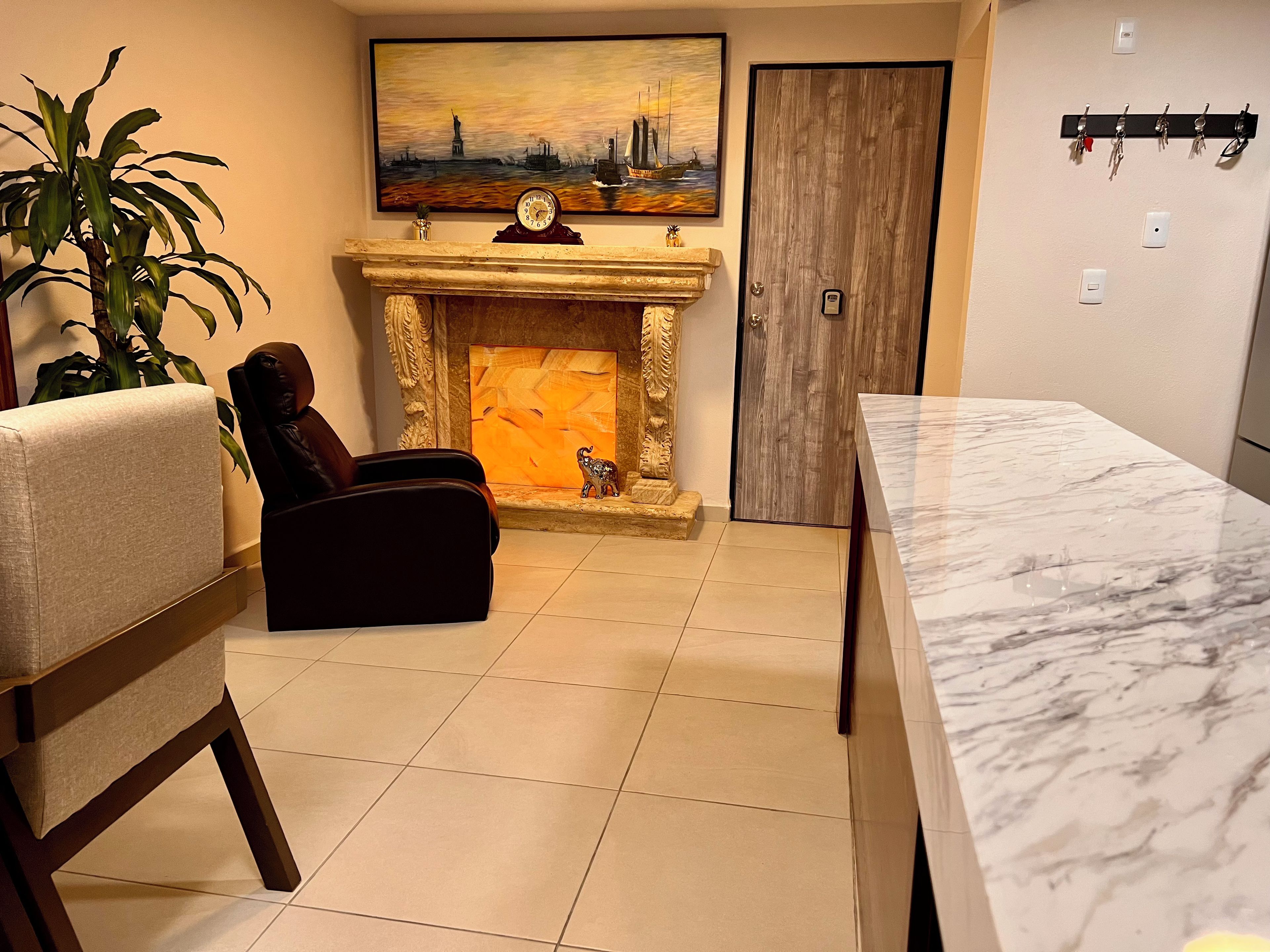 A living room with a fireplace, a sofa, a dining table, and a painting of a cityscape.