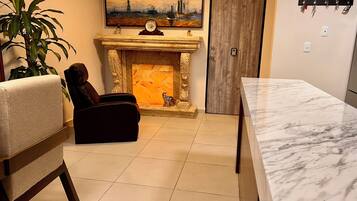 A living room with a fireplace, a sofa, a dining table, and a painting of a cityscape.