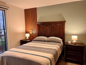 A bedroom with a bed, two bedside tables, a wall-mounted lamp, and a window. - New Listing (Galaxia la Calera)
