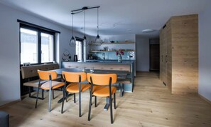 A modern kitchen with a central island, wooden flooring, and orange chairs. - PEACEFUL ZERMATT ESCAPE JUST MINUTES FROM SUNNEGGA & THE STATION (Zermatt)