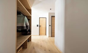 A hallway with a wooden bench, a coat rack with a jacket, and two doors. - PEACEFUL ZERMATT ESCAPE JUST MINUTES FROM SUNNEGGA & THE STATION (Zermatt)