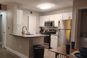 Une cuisine compacte dotée d’un îlot central, d’un four à micro-ondes, d’un réfrigérateur et d’une cuisinière.