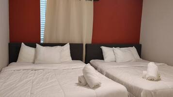 A hotel room with two beds, each with white bedding and pillows, and a red accent wall.
