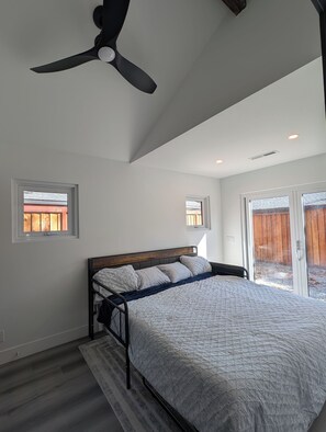 Una camera da letto con un letto, una ventola a soffitto, una finestra e una porta che dà su una zona esterna.