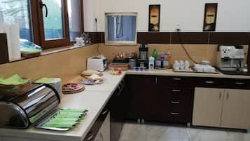 Una cocina con espacio tipo bufé, que incluye un tostador, una cafetera y diversos alimentos.
