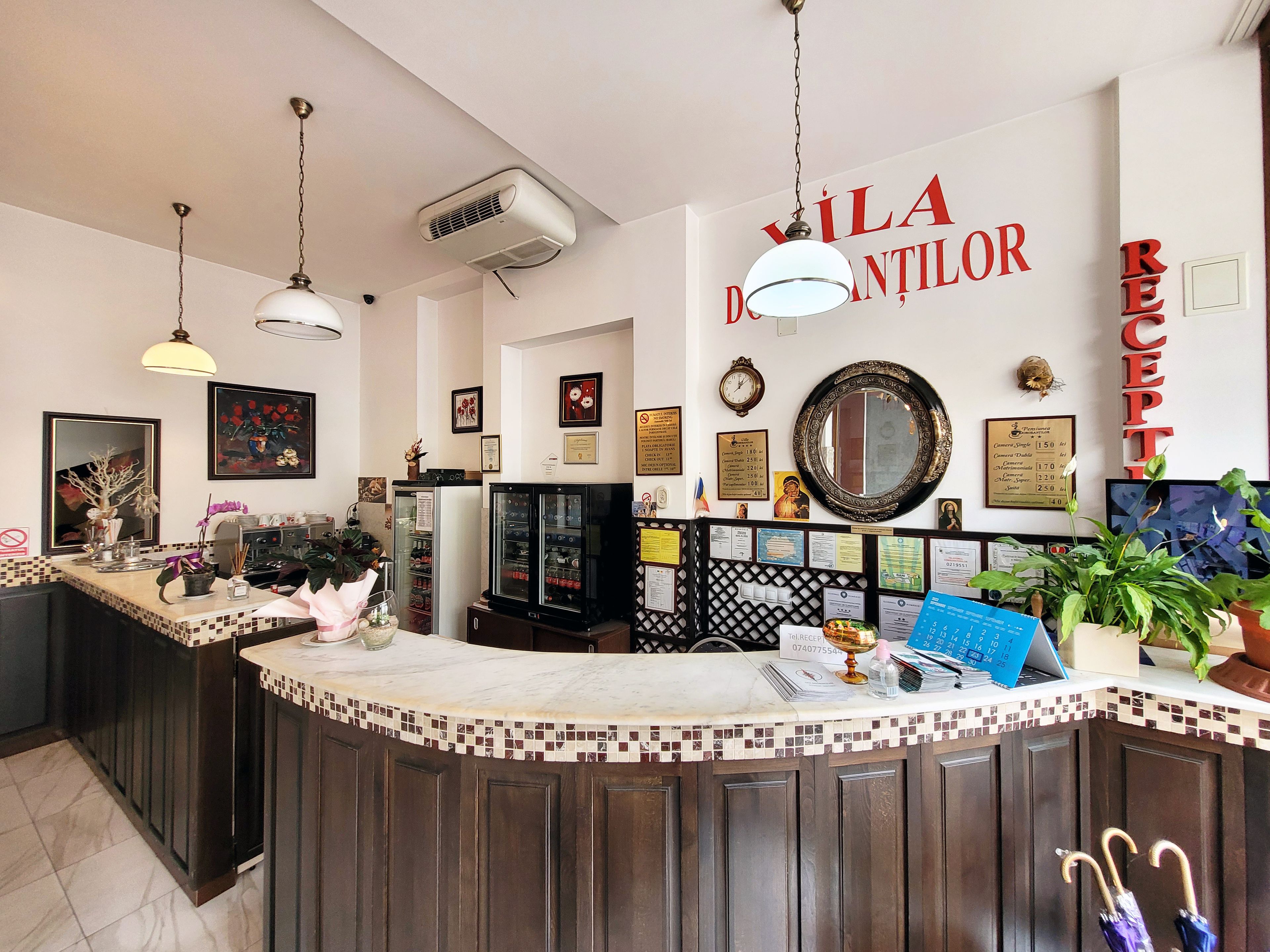 A reception area with a counter, a clock, framed pictures, and a mirror on the wall.