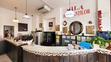 A reception area with a counter, a clock, framed pictures, and a mirror on the wall.